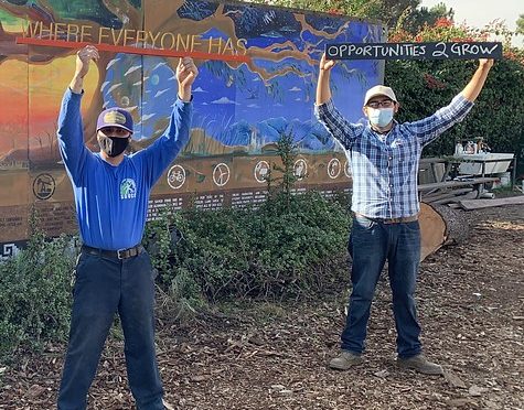 Two boys holding up a sign that says, "Where everyone has opportunities 2 Grow."